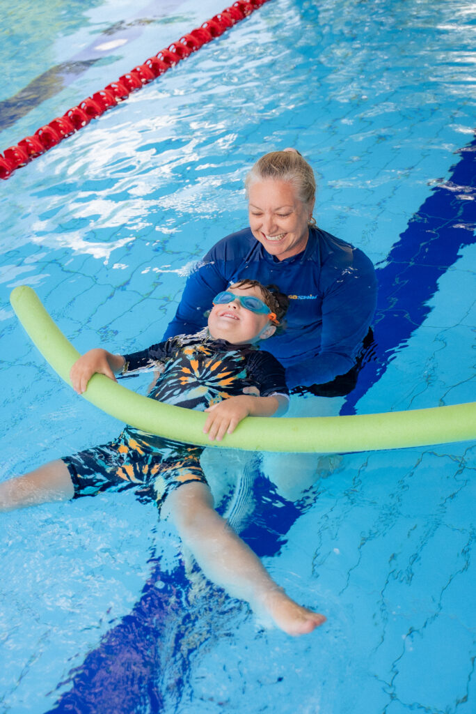 GOswim teacher assists young boy swimmer to float on his back